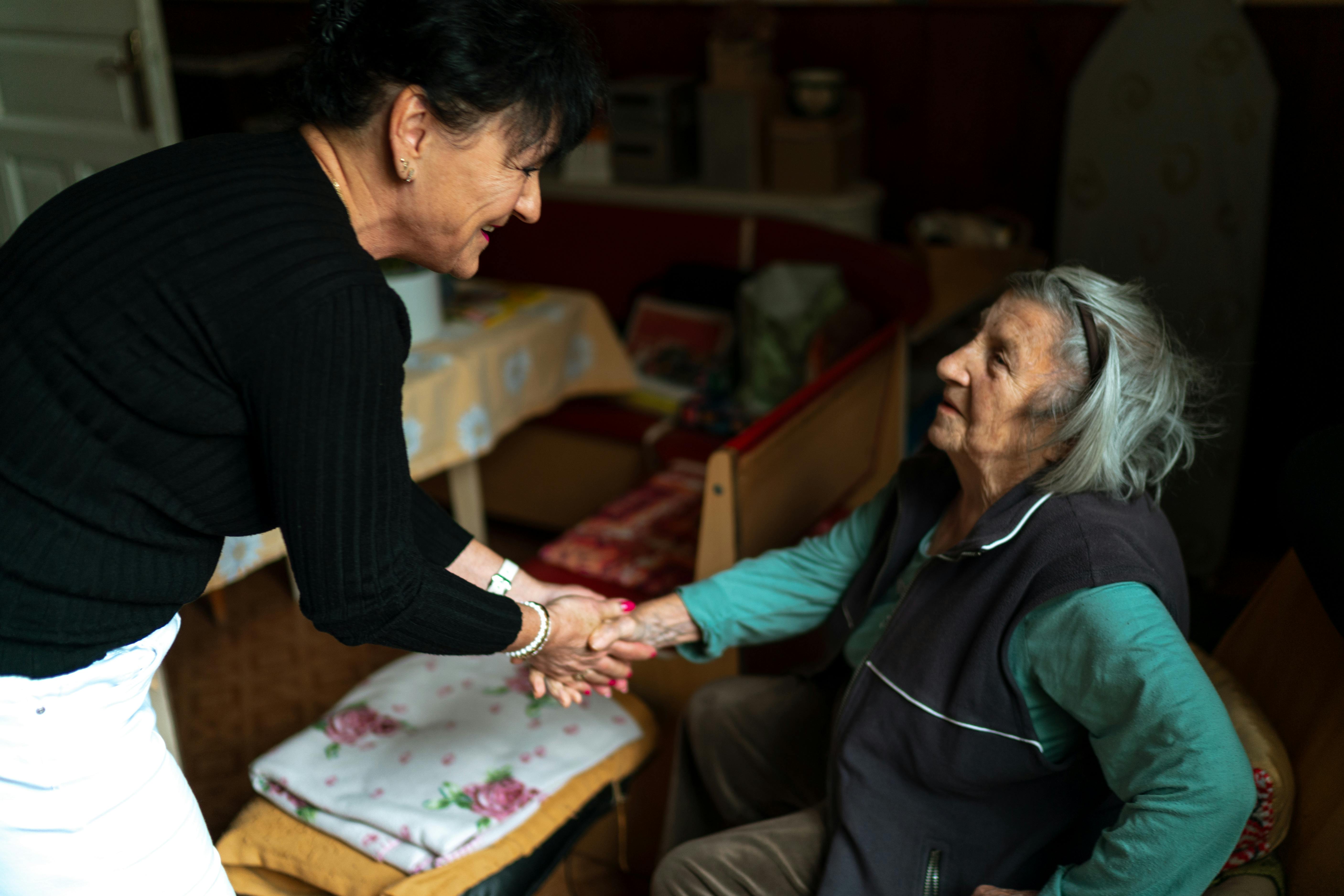 Caregiver greeting an older adult with a handshake